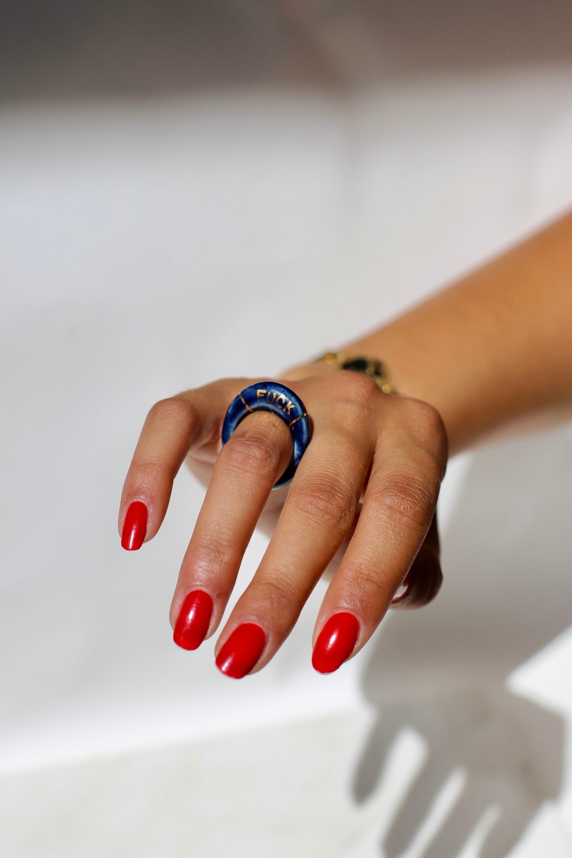 bague en porcelaine émaillée bleu nuit intense en taille 52 FR, avec fuck écrit en lettrage or peint à la main 