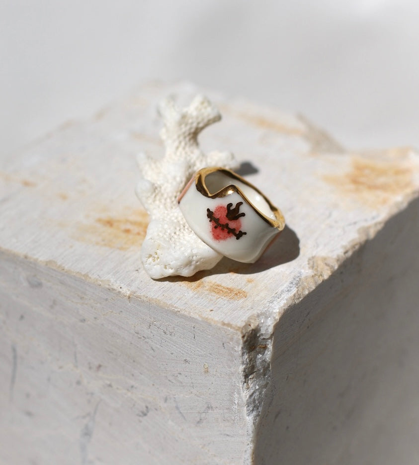 Bague asymétrique en porcelaine blanche émaillée en taille 52FR avec un motif coeur ex-voto peint à la main avec des détails en noirs et à l'or liquide. Fait à la main à Lyon