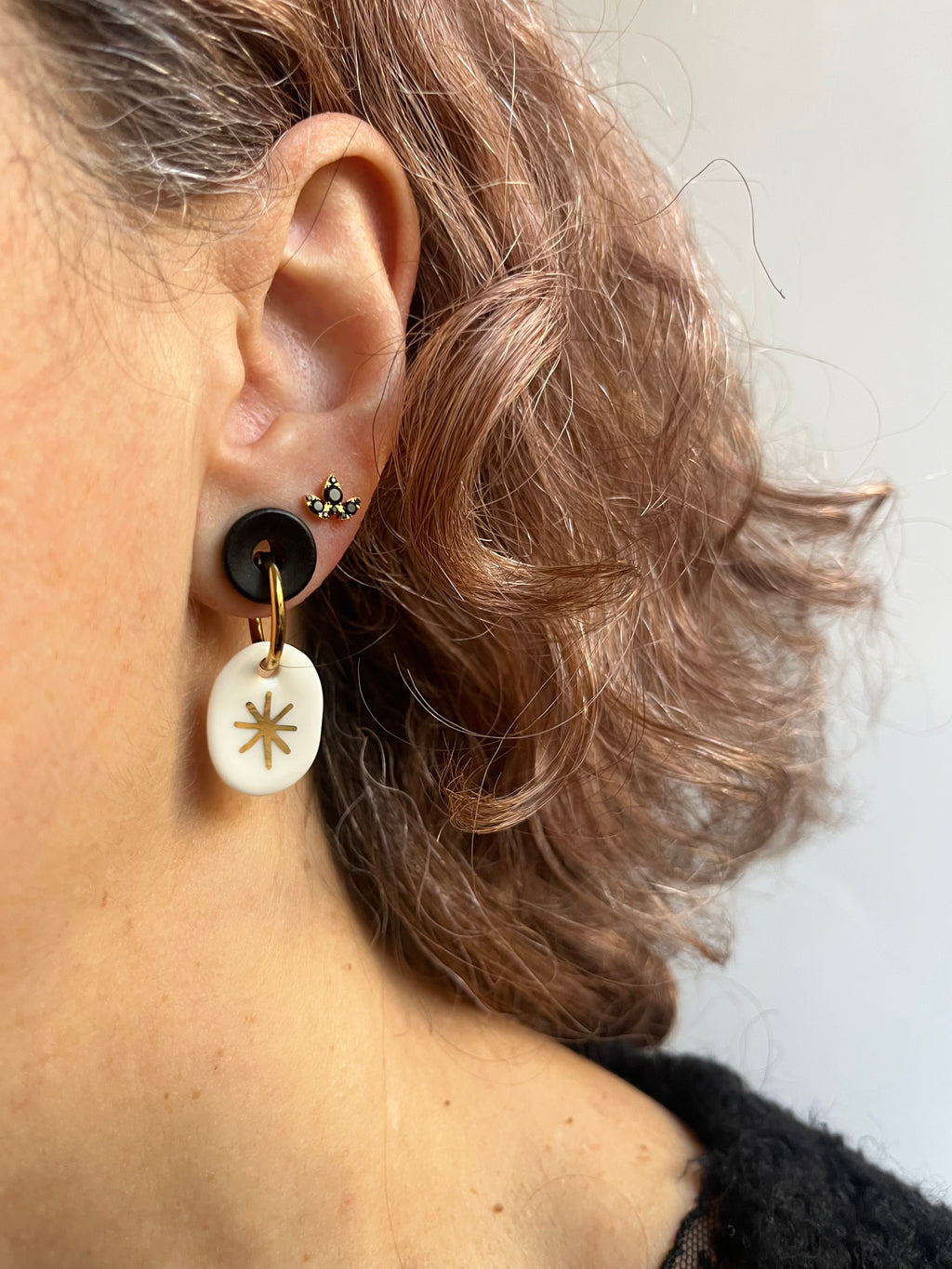 boucle d'oreille dorée avec son charm ovale en porcelaine blanche émaillée, avec un motif d'étoile céleste à l'or fait main