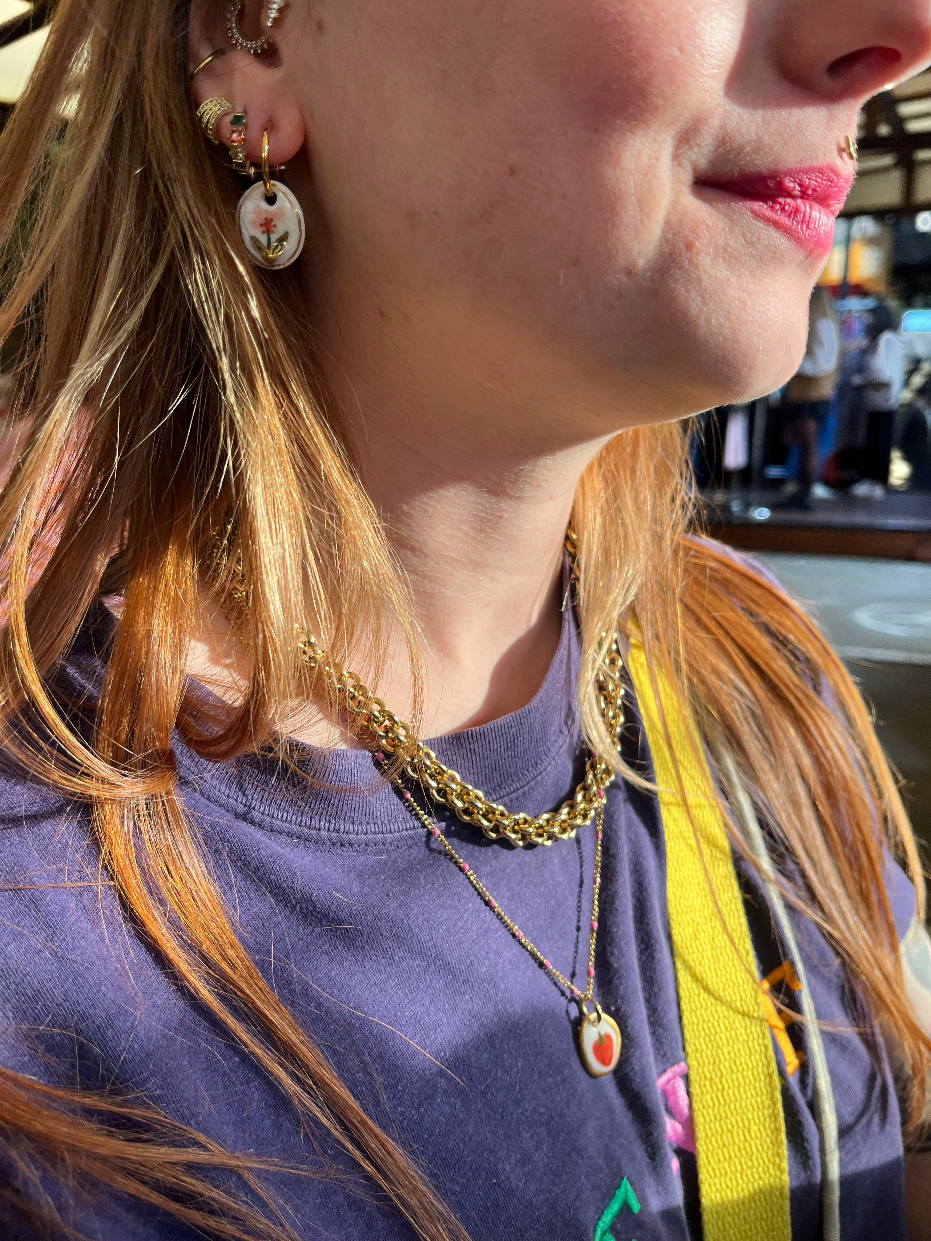 boucle d'oreille pendante dorée avec son médaillon ovale en porcelaine blanche, orné d'un motif floral  peint à la main.