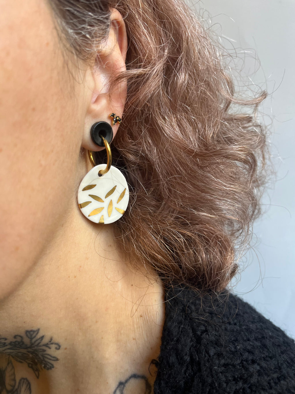 boucle d'oreille avec sa pendante en porcelaine blanche et ses petits motifs floraux dorés étincelants à l'or liquide.