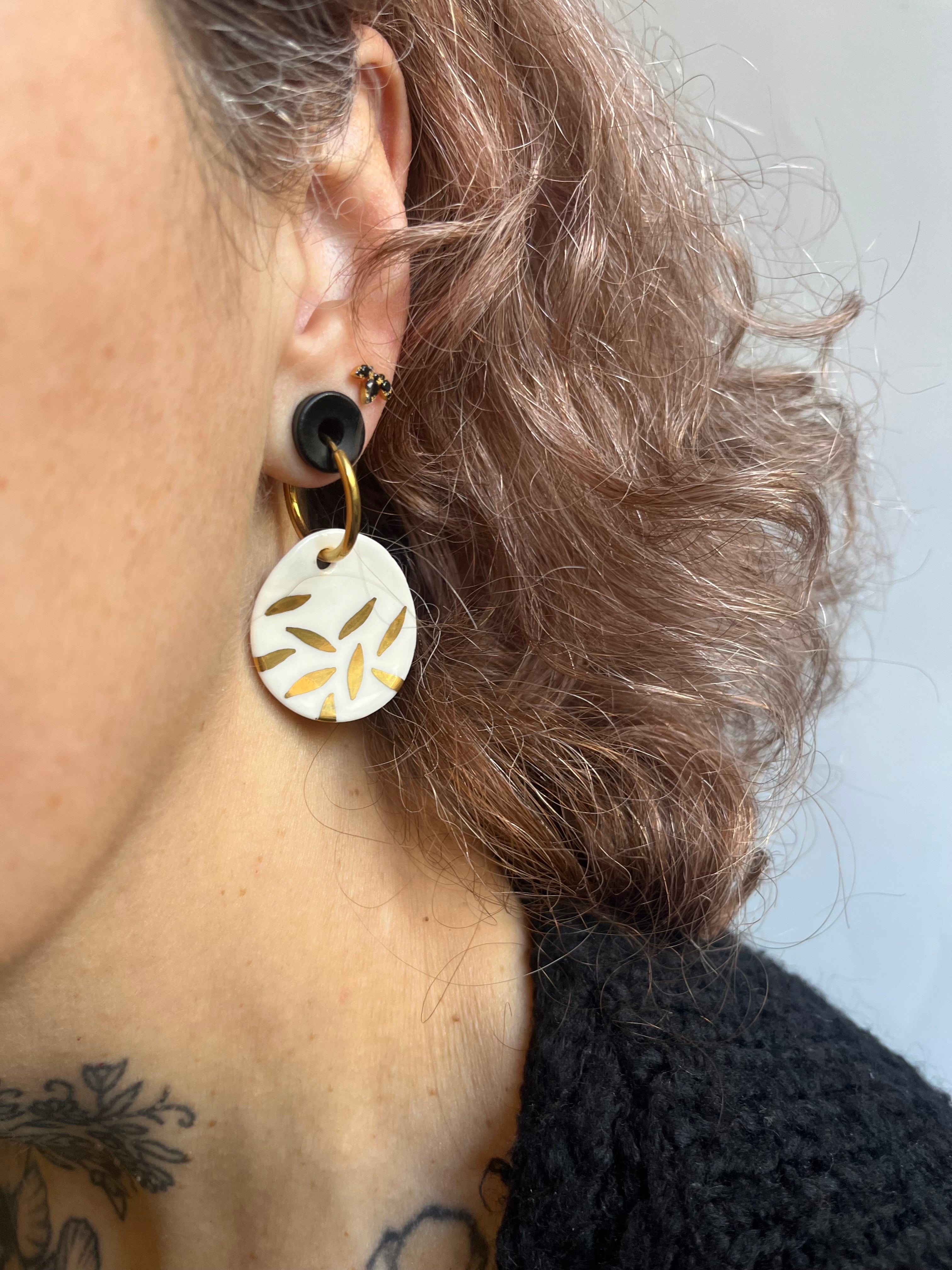 boucle d'oreille avec sa pendante en porcelaine blanche et ses petits motifs floraux dorés étincelants à l'or liquide.