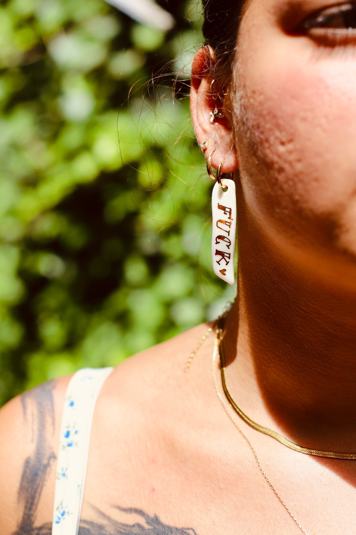 longue boucle d'oreille en porcelaine peint à la main avec une inscription du mot fuck à l'or liquide 