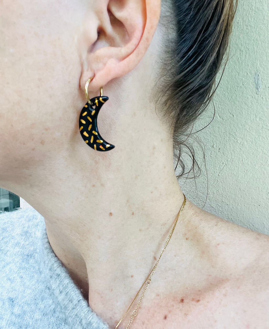 boucles d'oreilles noir  avec des pendentifs en forme de croissant de lune noir brillant et motifs pointillés dorés.
