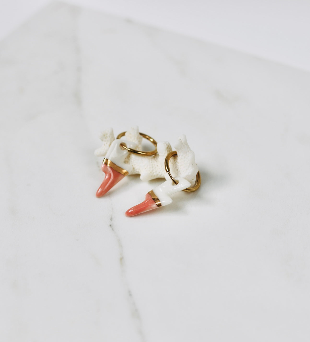 boucles d'oreilles dorées munies de charms éclairs en porcelaine bicolore blanc et rose saumon avec une démarcation à l'or fin réalisé à la main à Lyon. 