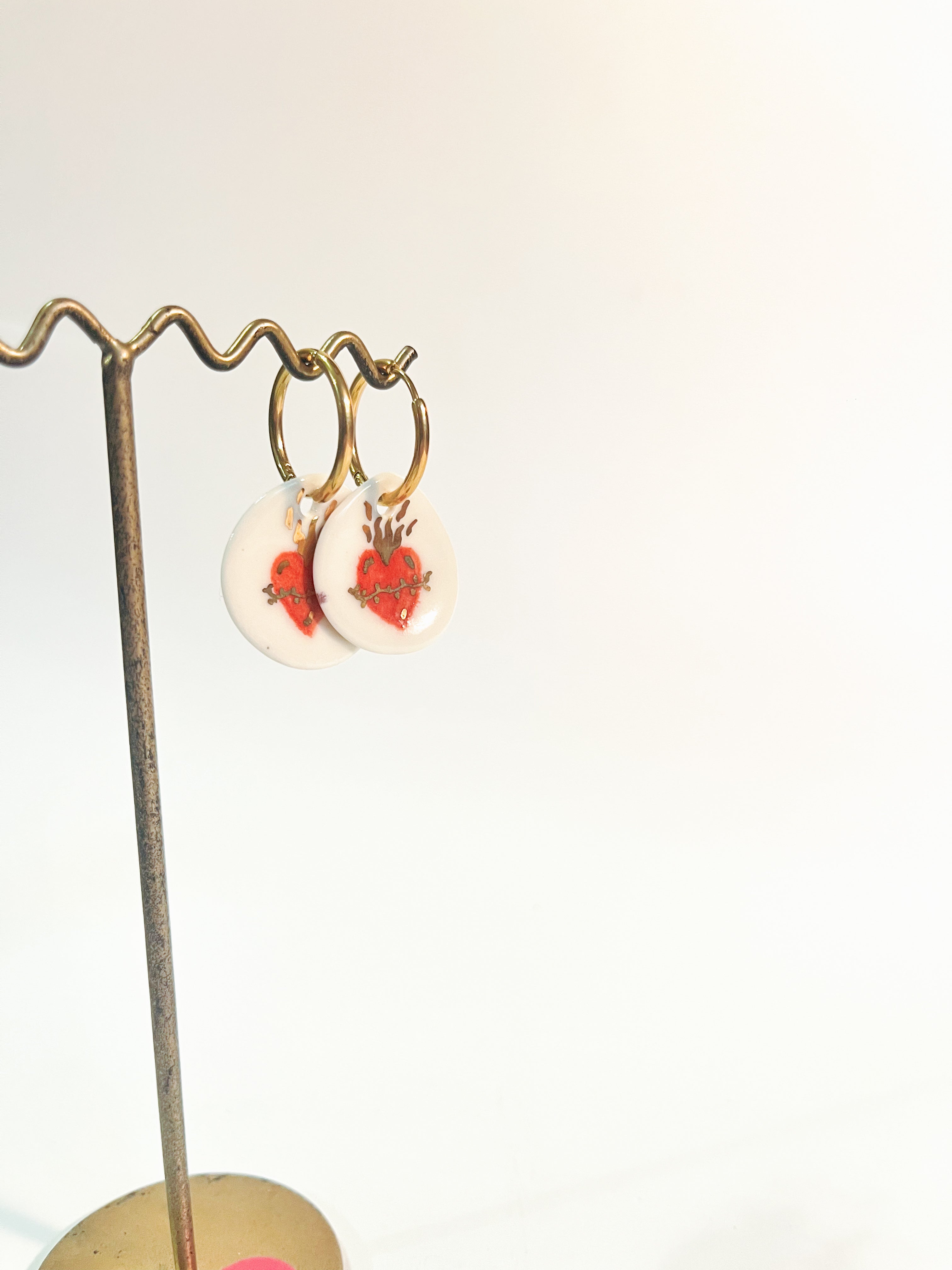 Paire de boucles d'oreilles dorées  en porcelaine blanche ronde avec un motif de cœur ex-voto rouge et de flammes d'or peint à la main 