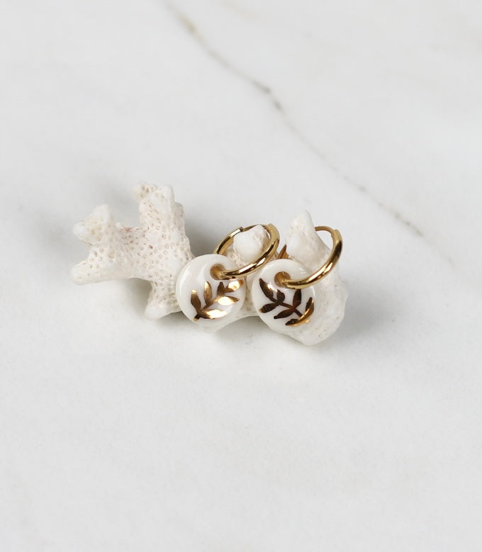 Paire de petites boucles d'oreilles dorées  en porcelaine blanche émaillée, ornées d'une branche de feuilles finement peinte à l'or fin étincelant fait à la main.