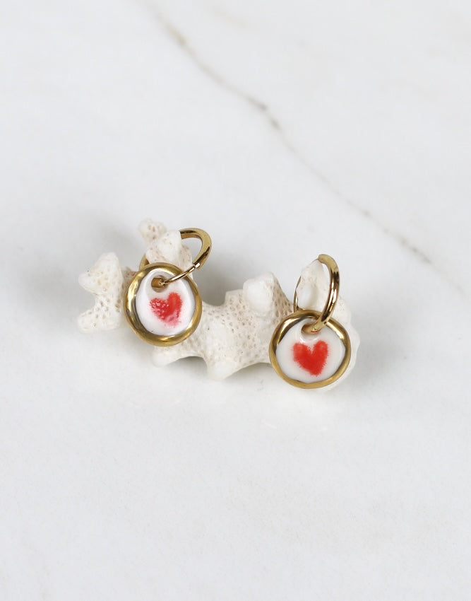 Paire de boucles d'oreilles pendantes avec petits médaillons ronds en porcelaine blanche émaillée, ornés d'un cœur rouge peint au centre et d'une bordure dorée à l'or fin fait à la main 