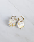 Paire de boucles d'oreilles dorées avec médaillons pendants de forme ovale en porcelaine blanche, ornés de motif floral d'or.