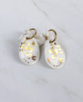 Paire de boucles d'oreilles pendantes symboliques en porcelaine blanche et or fin. Motif serpent sinueux, étoile et lune peints à la main 