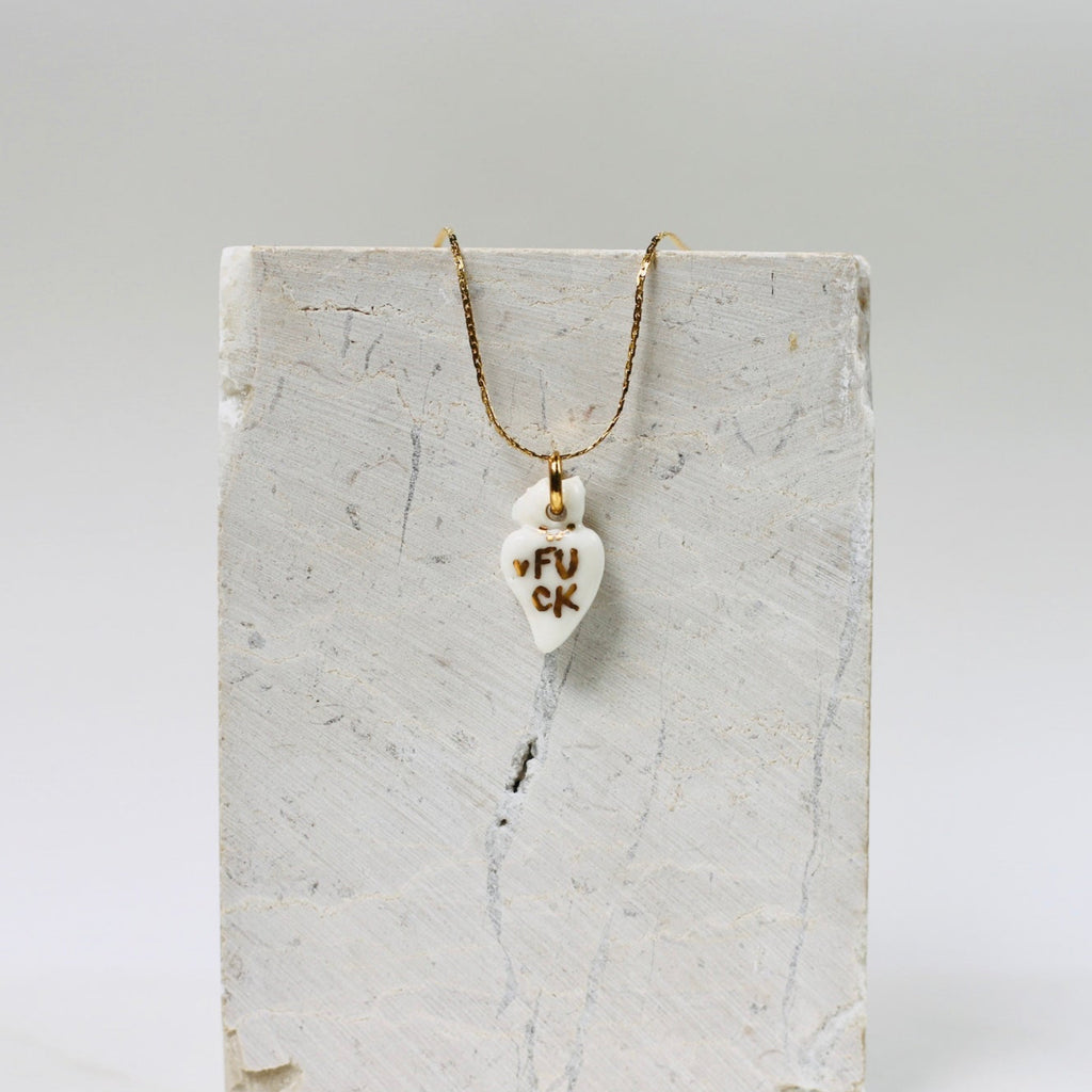 Collier fin avec un pendentif en porcelaine blanche en forme de cœur ex-voto,  avec un message FUCK écrit en or fait à la main 