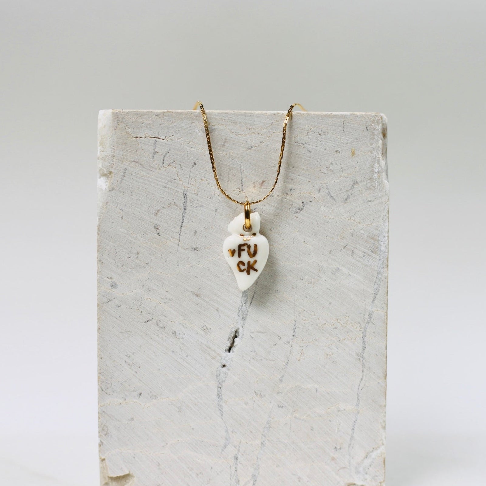 Collier fin avec un pendentif en porcelaine blanche en forme de cœur ex-voto,  avec un message FUCK écrit en or fait à la main 