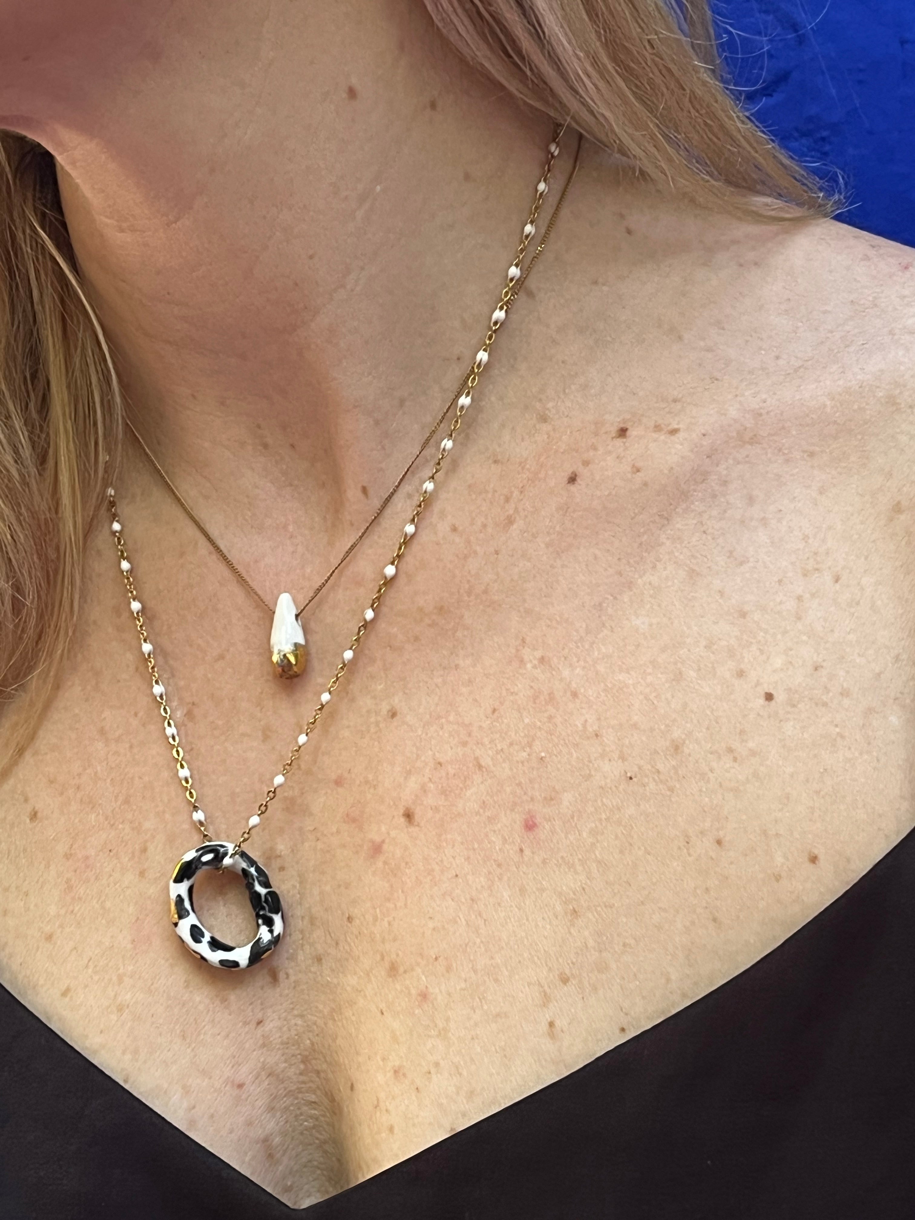 collier artisanal en porcelaine avec une goutte blanche et sa finition dorée brillante à l'or liquide sur sa moitié inférieure.