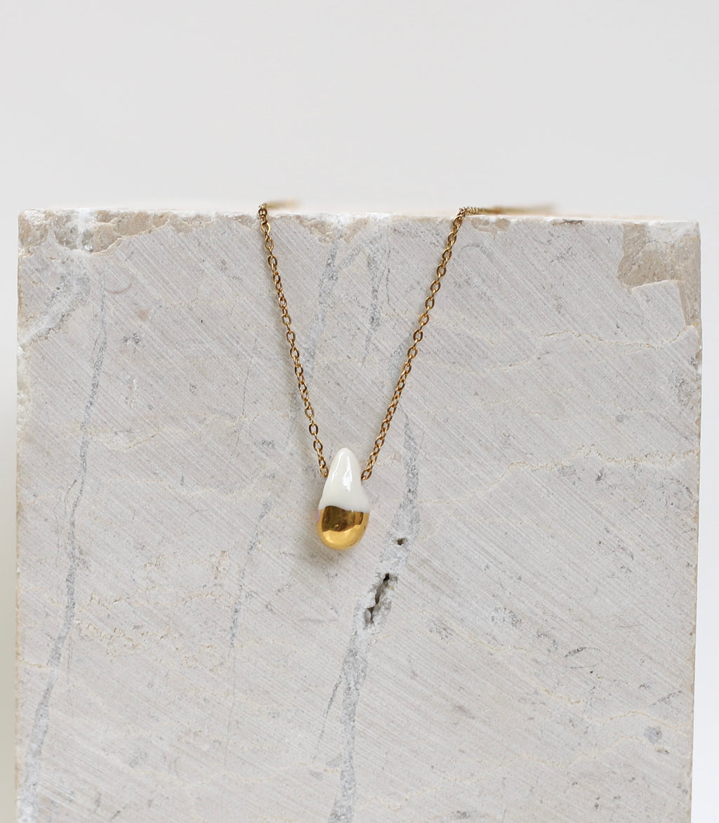 Collier fin  doté d'un pendentif en forme de goutte en porcelaine blanche dont la partie inférieure est recouverte d'or fin brillant.