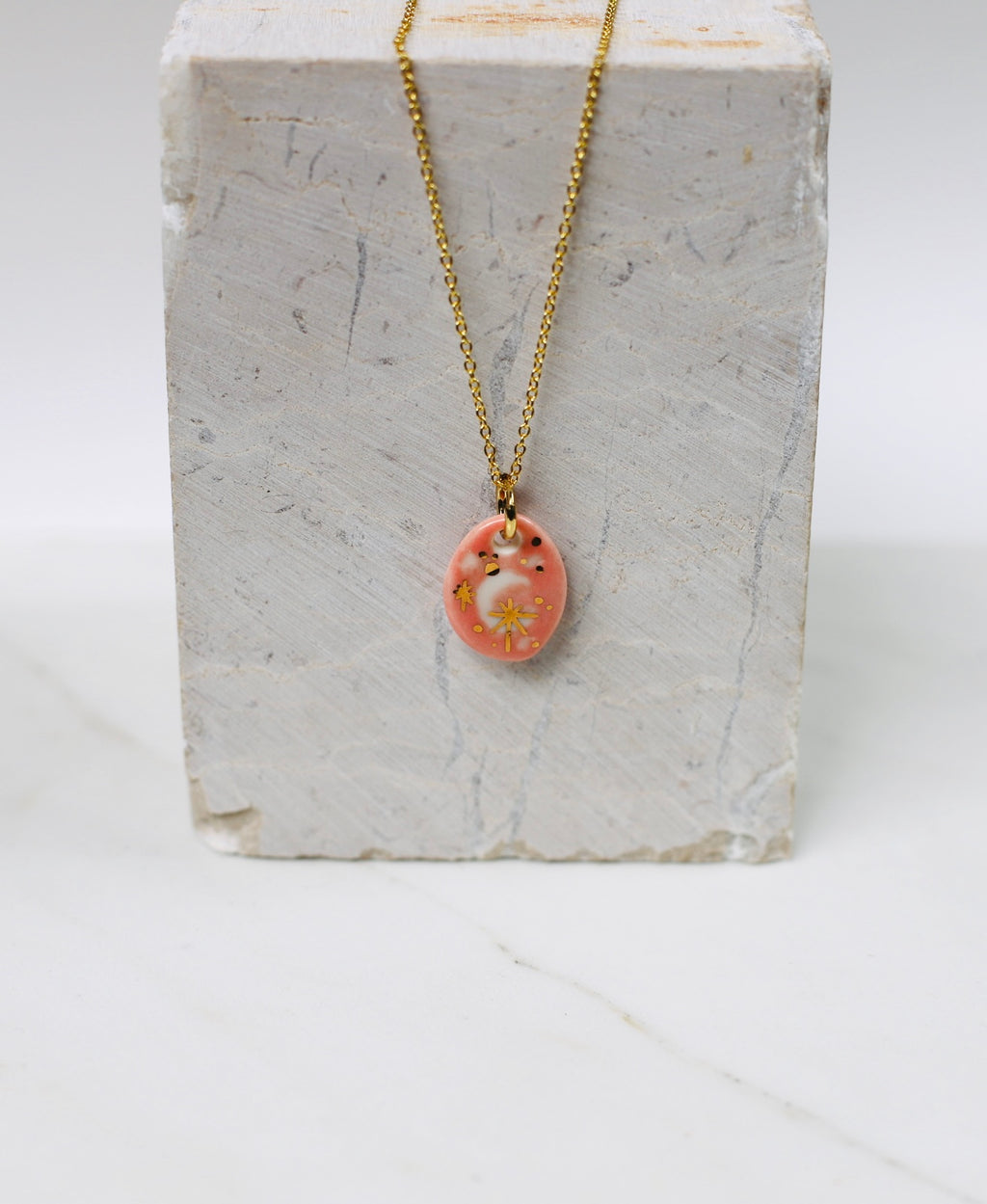 Collier un pendentif en forme de Lune  en porcelaine rose, avec des détail à l'or brillant 
