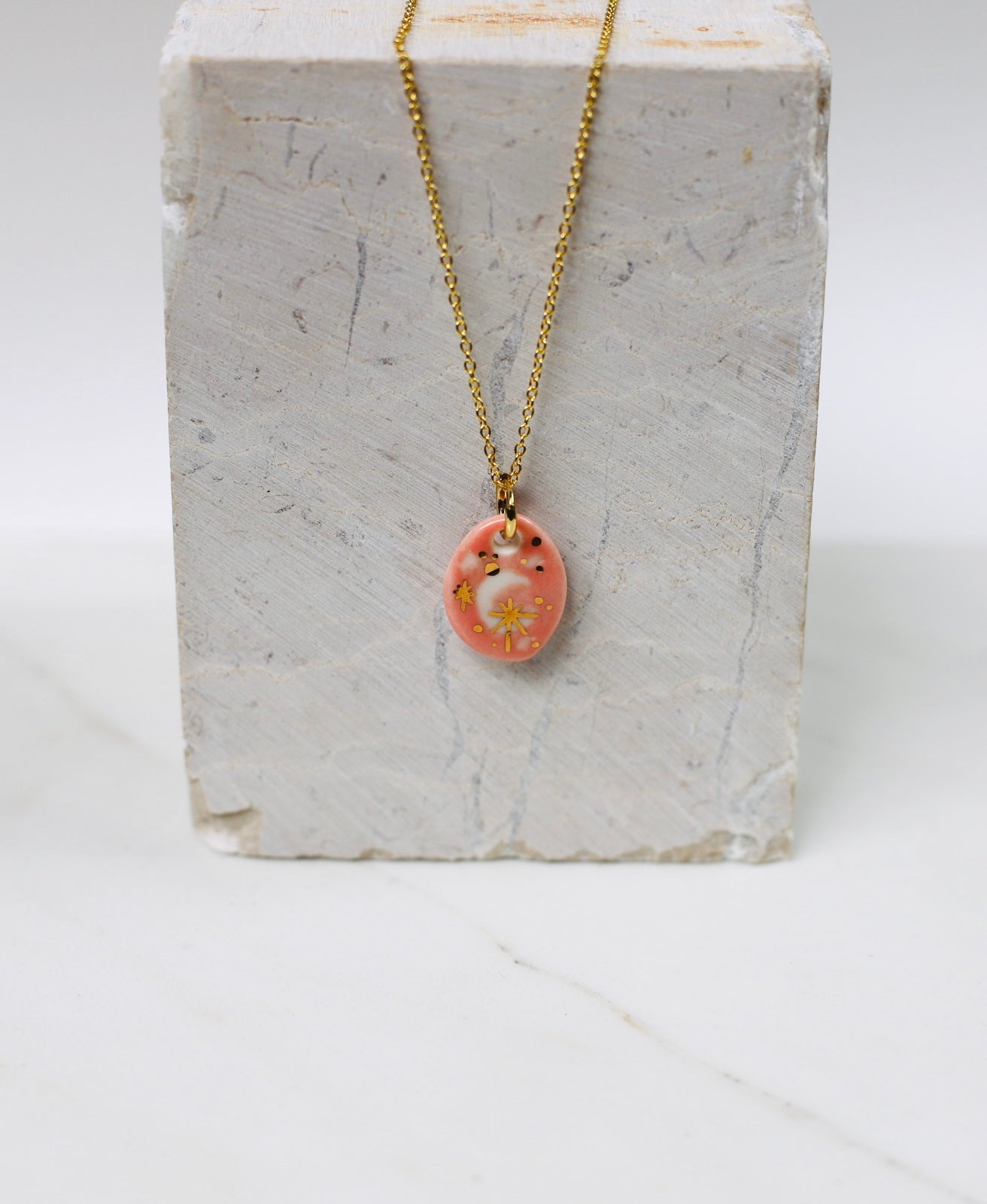 Collier un pendentif en forme de Lune  en porcelaine rose, avec des détail à l'or brillant 