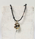 collier en fines perles noires orné d'un pendentif galet en porcelaine blanche avec un imprimé léopard tacheté noir et or fin fait main 