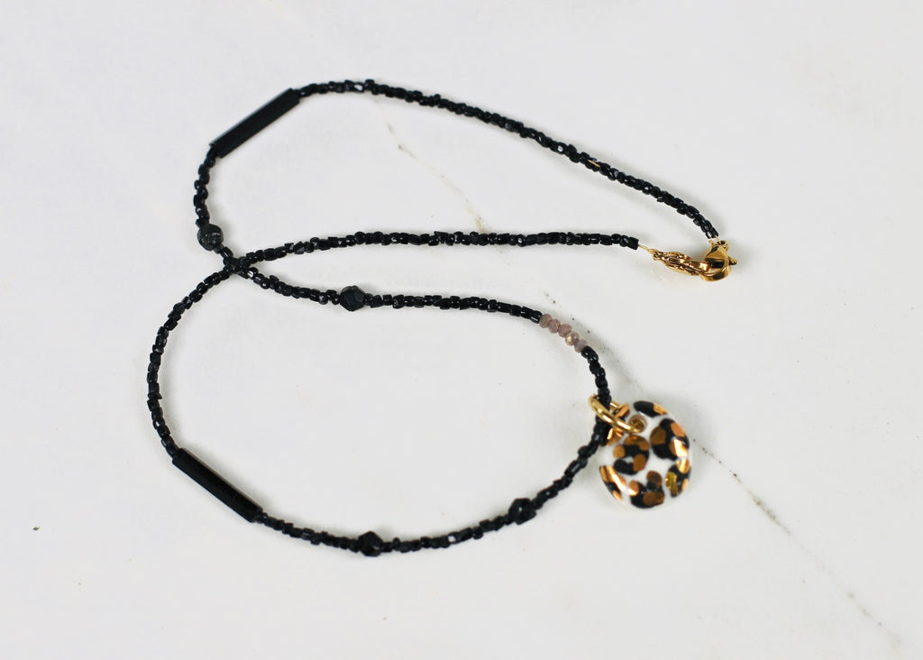 Collier en perles noires avec un pendentif à motif léopard en porcelaine taché d'or.