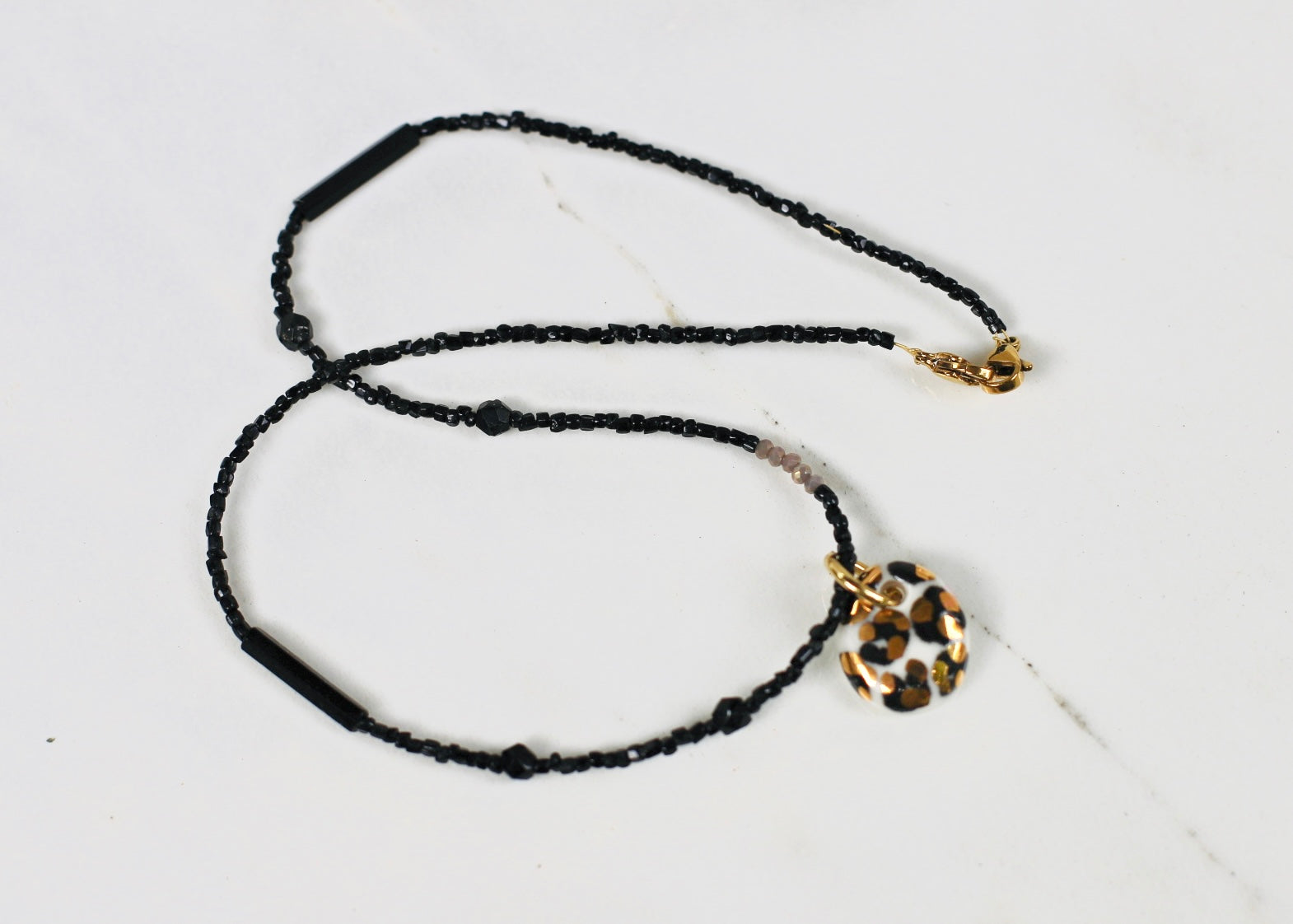 Collier en perles noires avec un pendentif à motif léopard en porcelaine taché d'or.