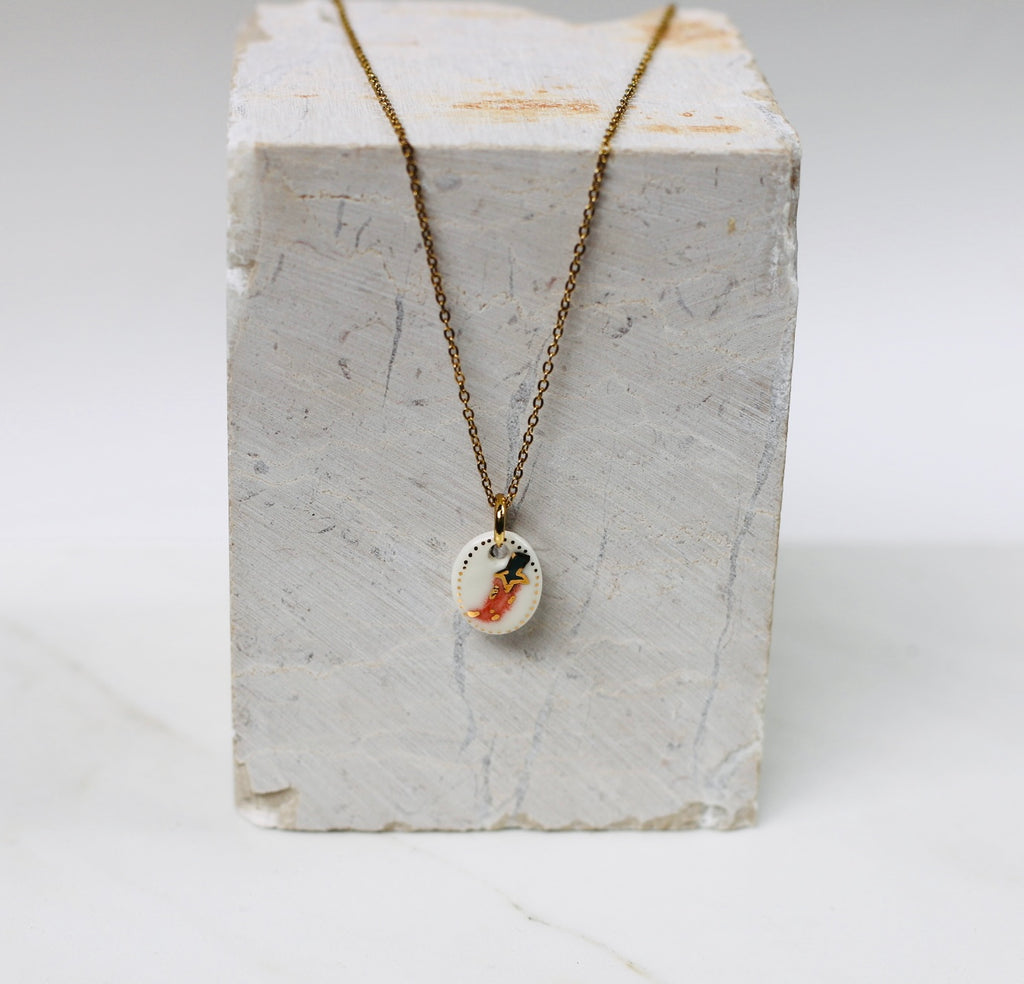 collier avec un pendentif  en motif de piment en porcelaine blanche, avec détail à l'or liquide 