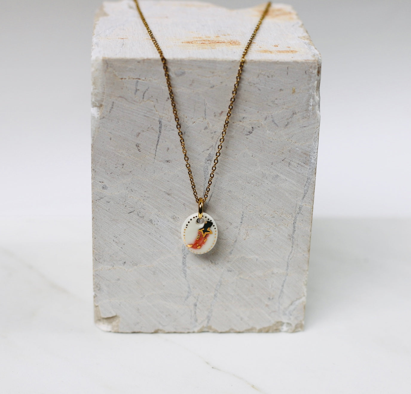 collier avec un pendentif  en motif de piment en porcelaine blanche, avec détail à l'or liquide 