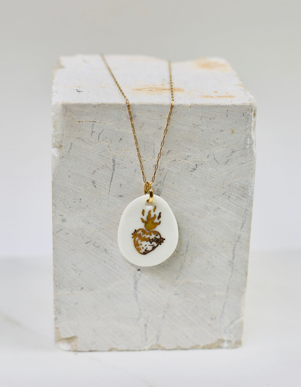 Collier fin pour femme avec un pendentif en porcelaine blanche orné d'un motif sacré-cœur ex-voto enflammé peint à l'or fin.
