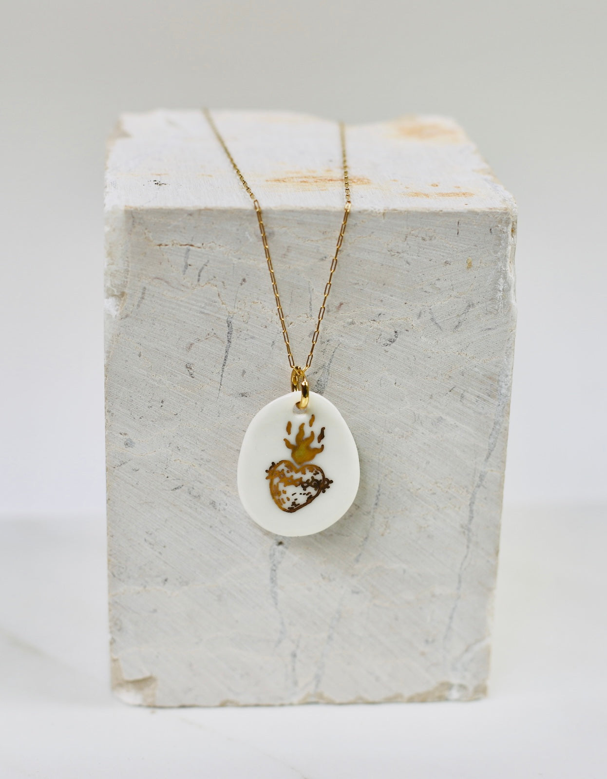 Collier fin pour femme avec un pendentif en porcelaine blanche orné d'un motif sacré-cœur ex-voto enflammé peint à l'or fin.