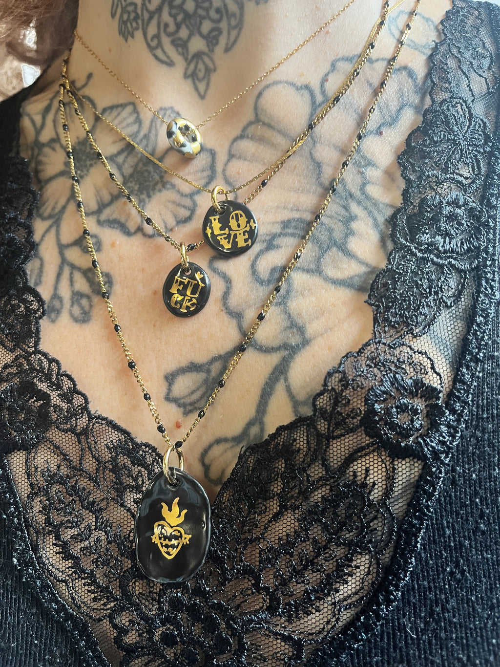 collier avec pendentif galet en porcelaine noire et sacré-cœur doré, monté sur une fine chaîne dorée ornée de mini perles noires. création lyonnais