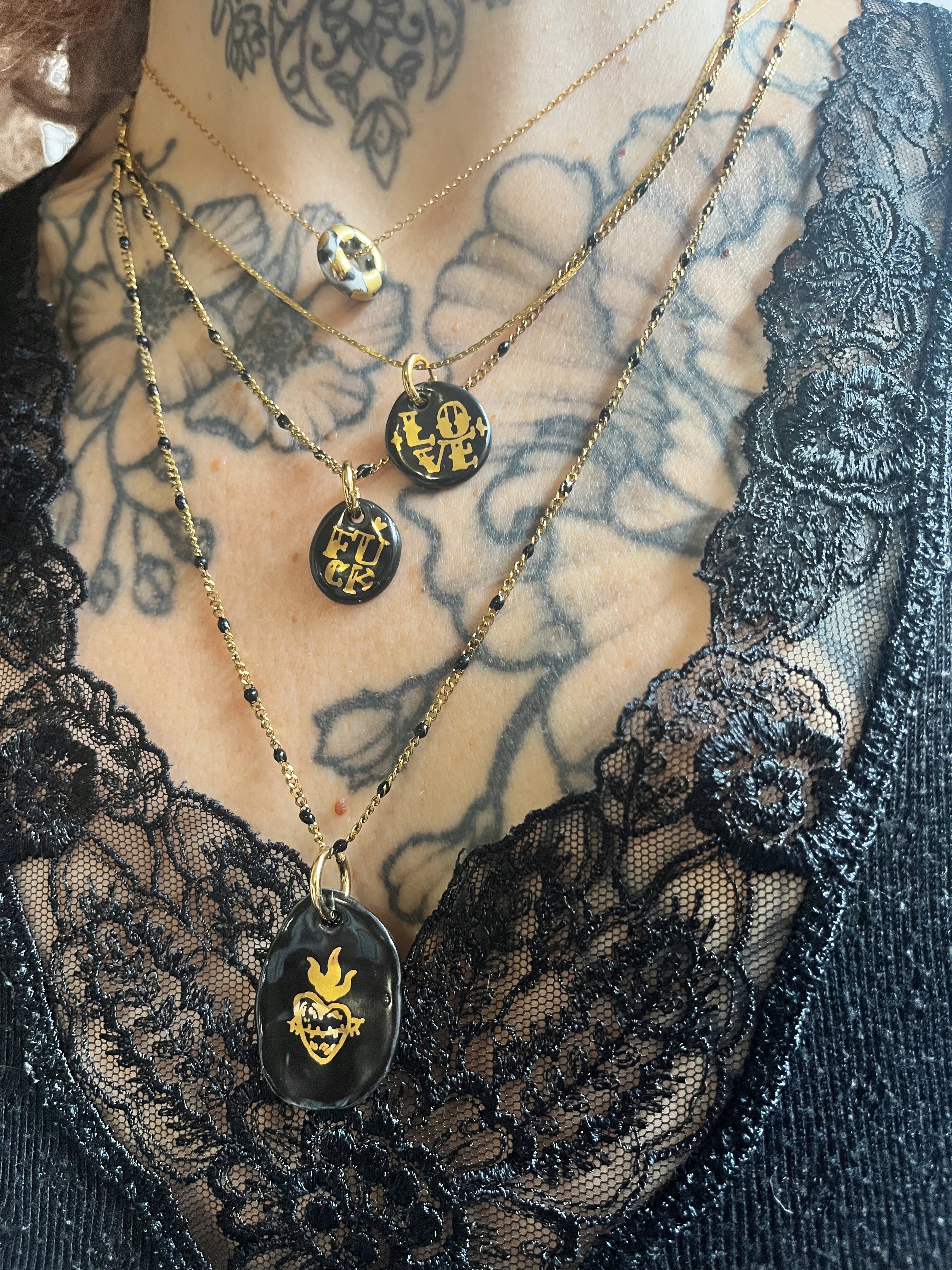 collier avec pendentif galet en porcelaine noire et sacré-cœur doré, monté sur une fine chaîne dorée ornée de mini perles noires. création lyonnais