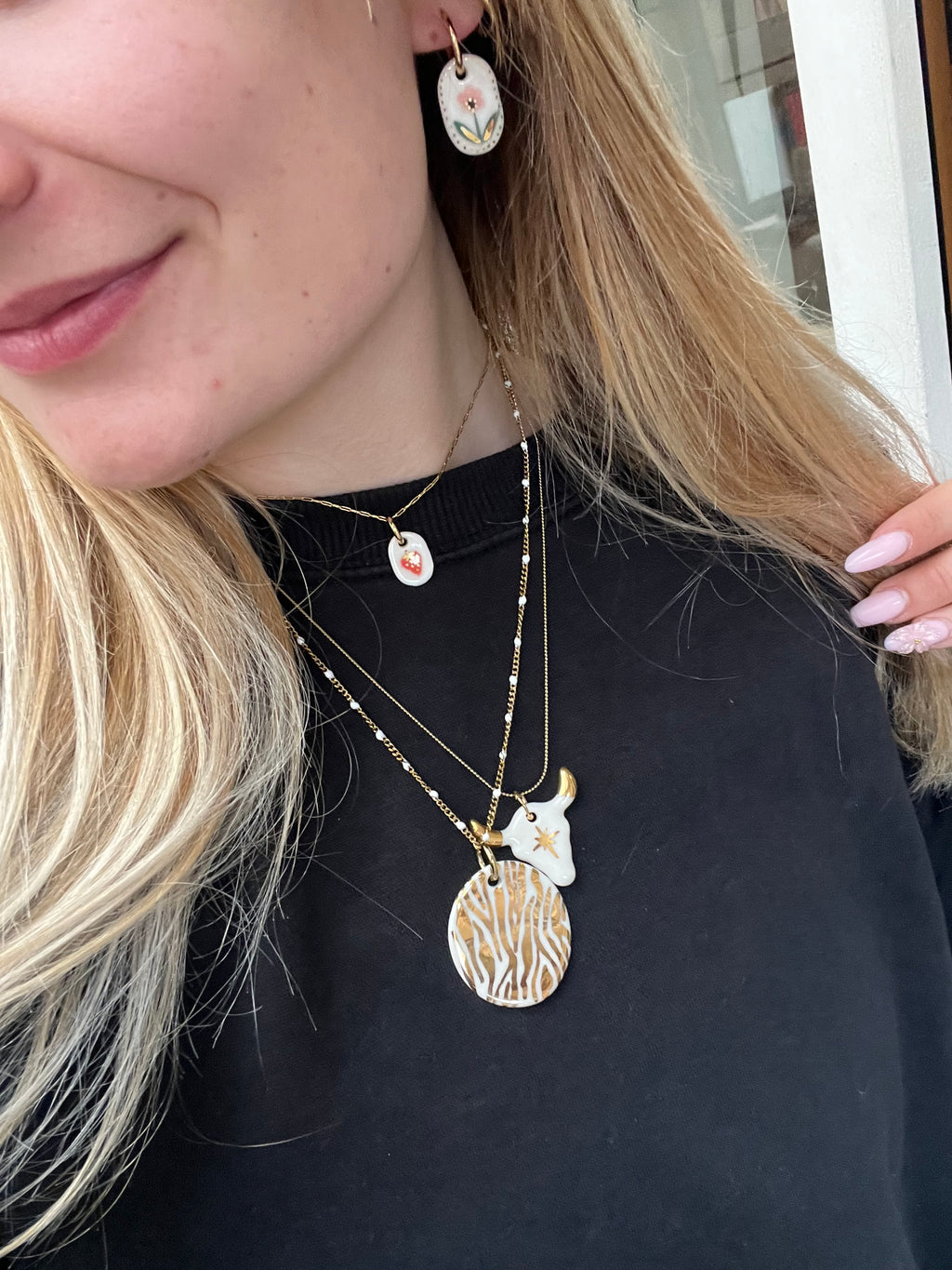 Collier à grosse chaîne dorée avec un pendentif tête de taureau en porcelaine blanche avec plusieurs détail peint à l'or liquide