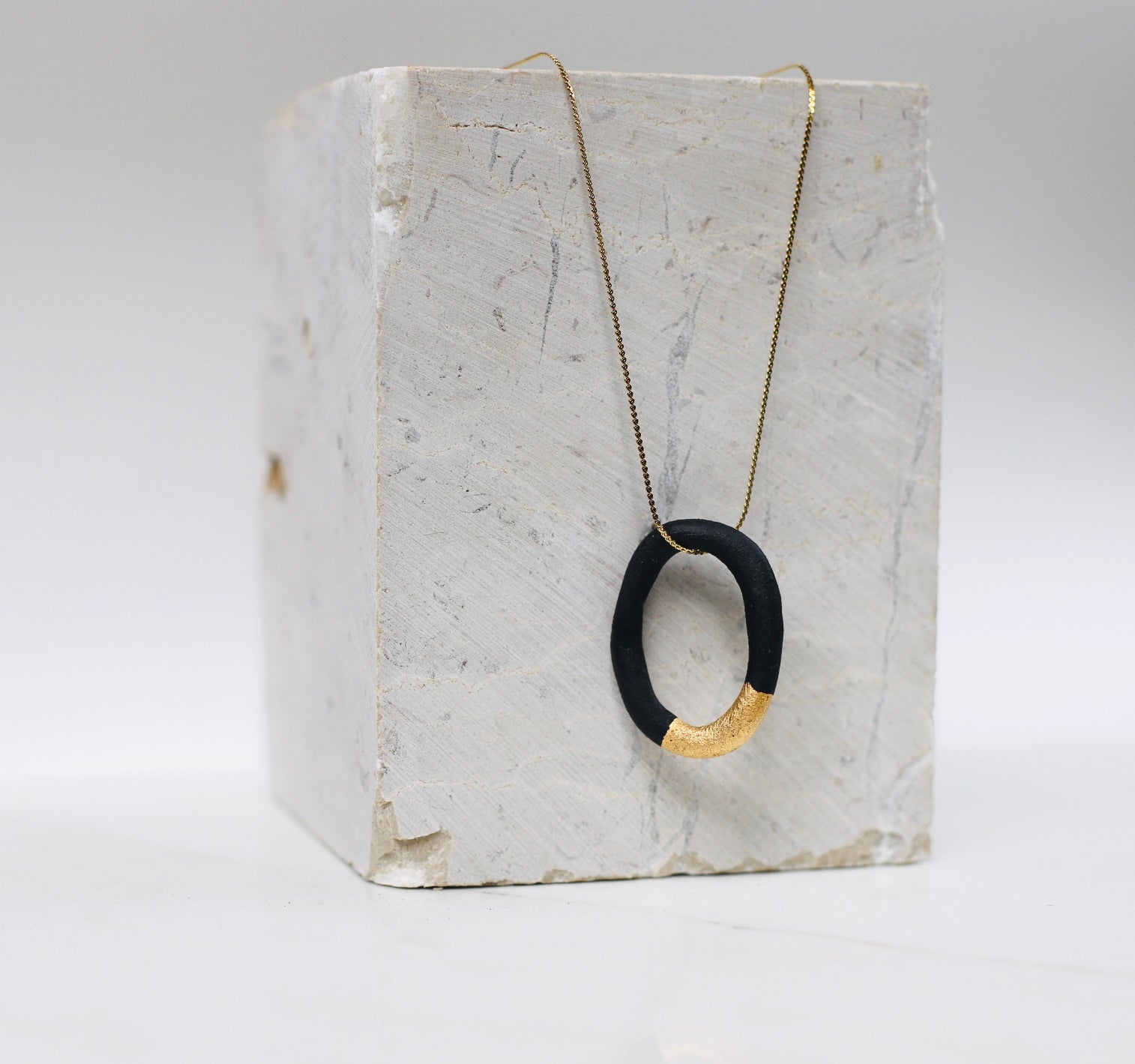 paire de boucles d'oreilles créoles en porcelaine noirs mats avec une touche d'or liquide fais à la main. 