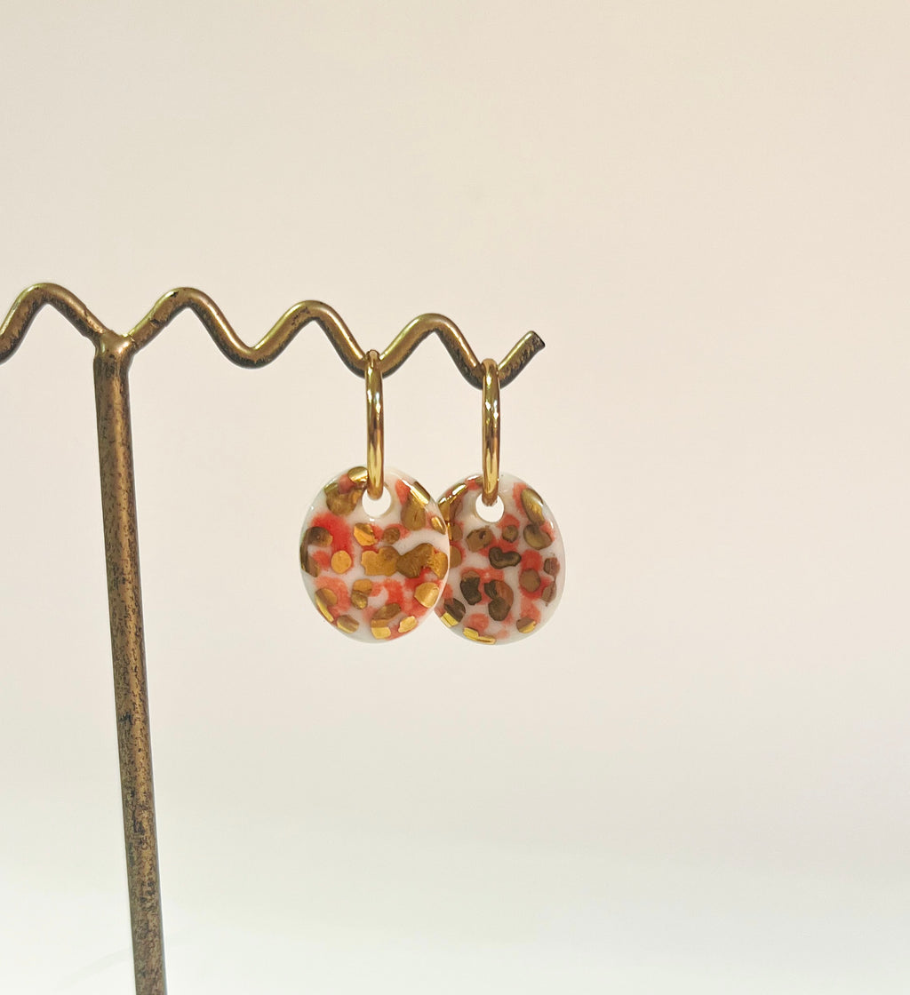 boucles d'oreilles circulaires en porcelaine blanche à motifs animaliers tachetés fait à la main avec des détails à l'or liquide.
