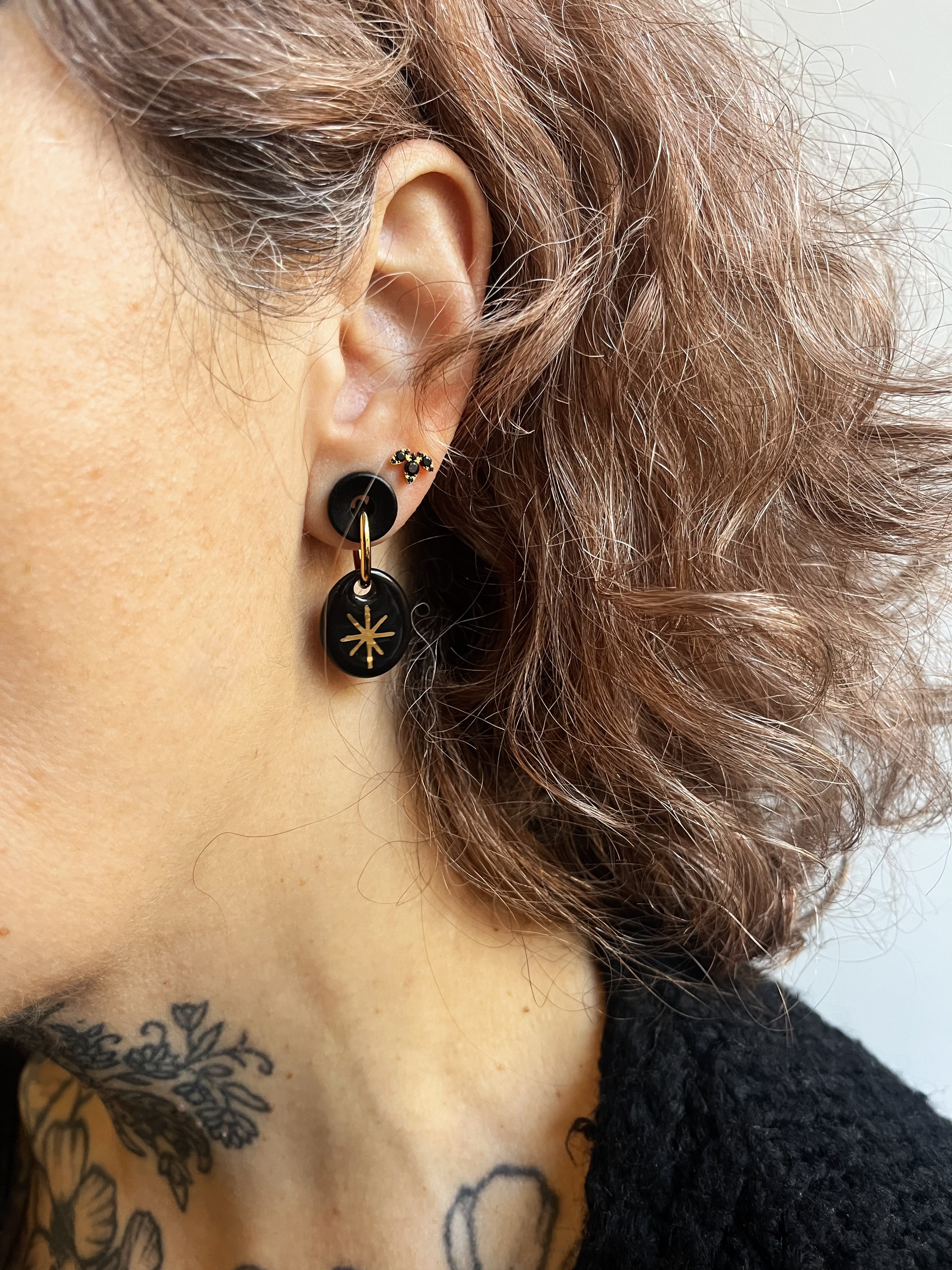 Boucle d'oreille noir avec un motif illustrant une étoile dorée à l'or liquide fait à la main