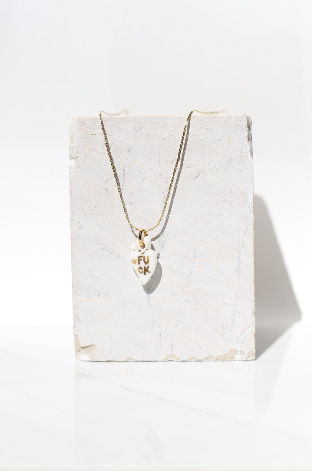 pendentif en porcelaine blanche en cœur ex-voto sacré avec 'inscription FUCK fait main à Lyon 