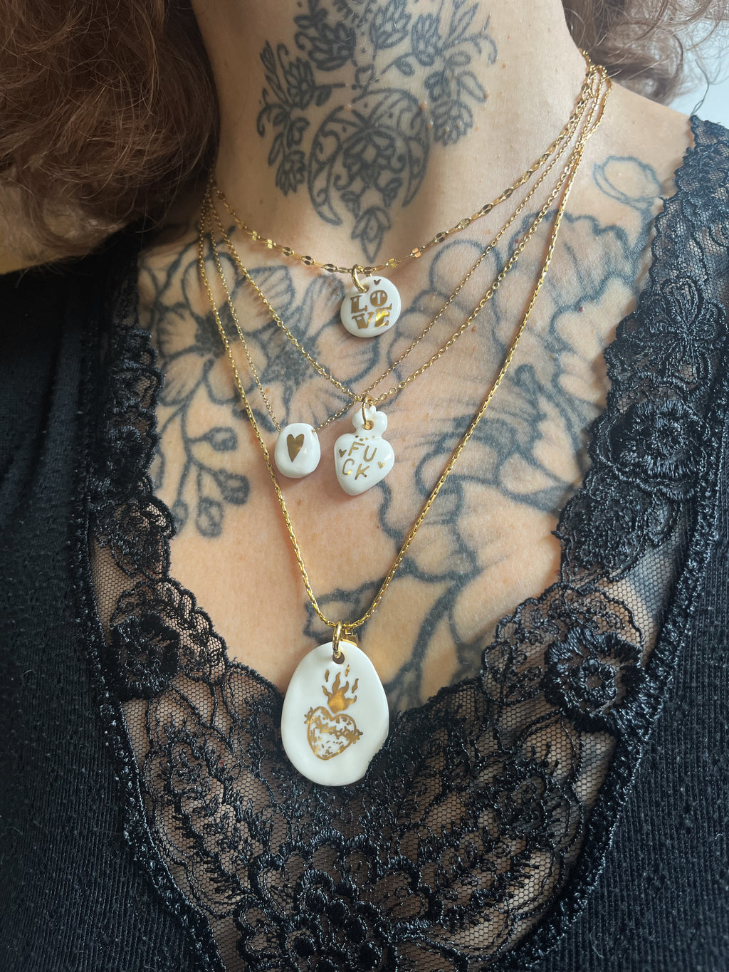 Collier avec un motif en forme de coeur abordant le mot fuck en porcelaine blanche émaillée, peint à la main à Lyon.