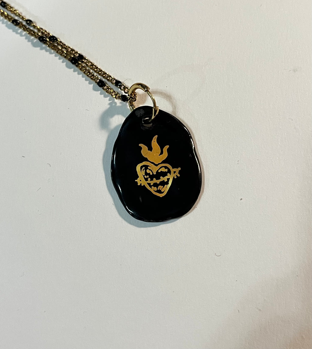collier médaille en porcelaine noire émaillée représentant un sacré-cœur ex-voto dessiné à la main à l'or fin liquide.
