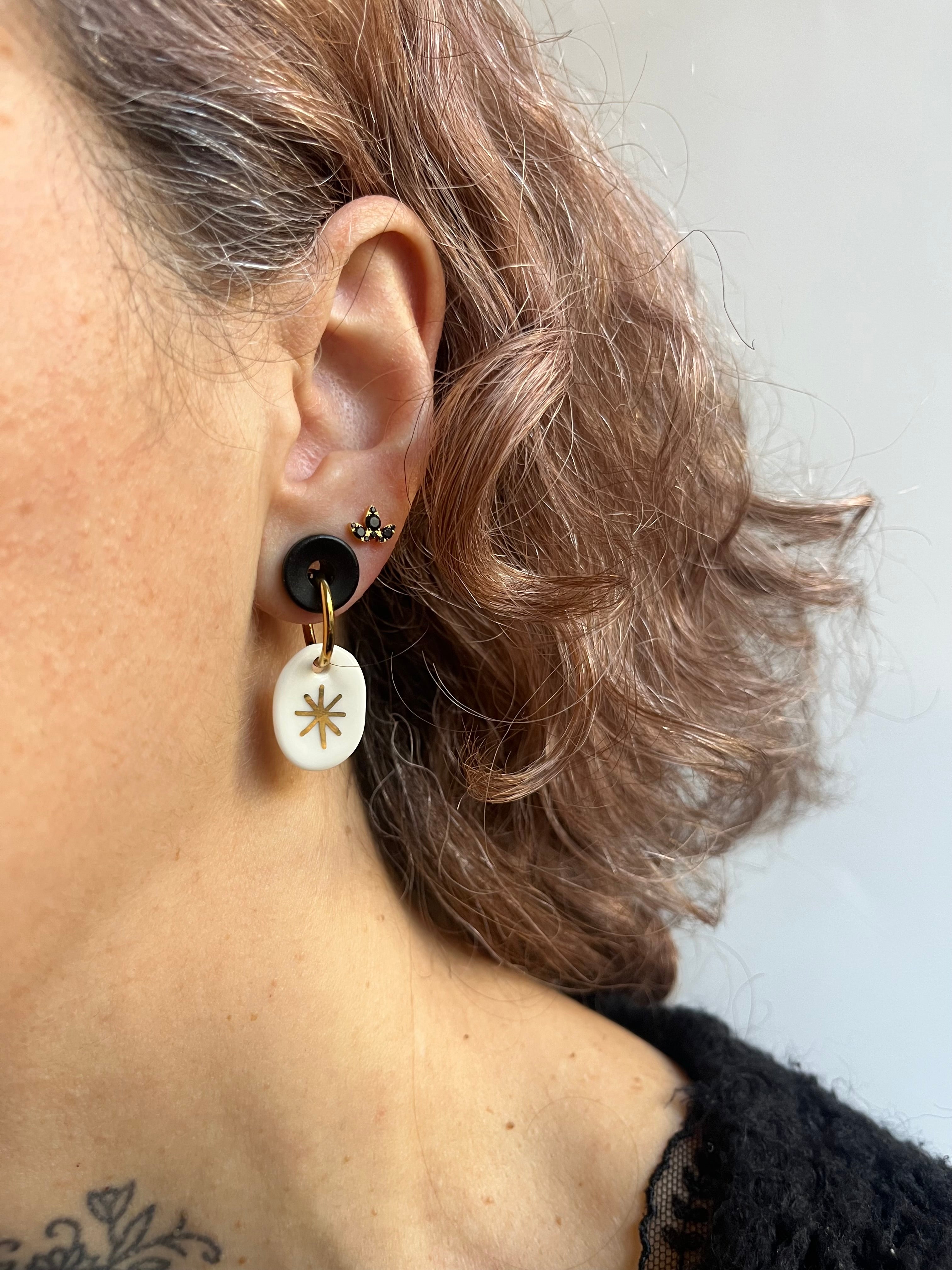boucle d'oreille avec une médaille ovale en porcelaine fine, avec comme motif une étoile dorée entièrement peinte à la main.