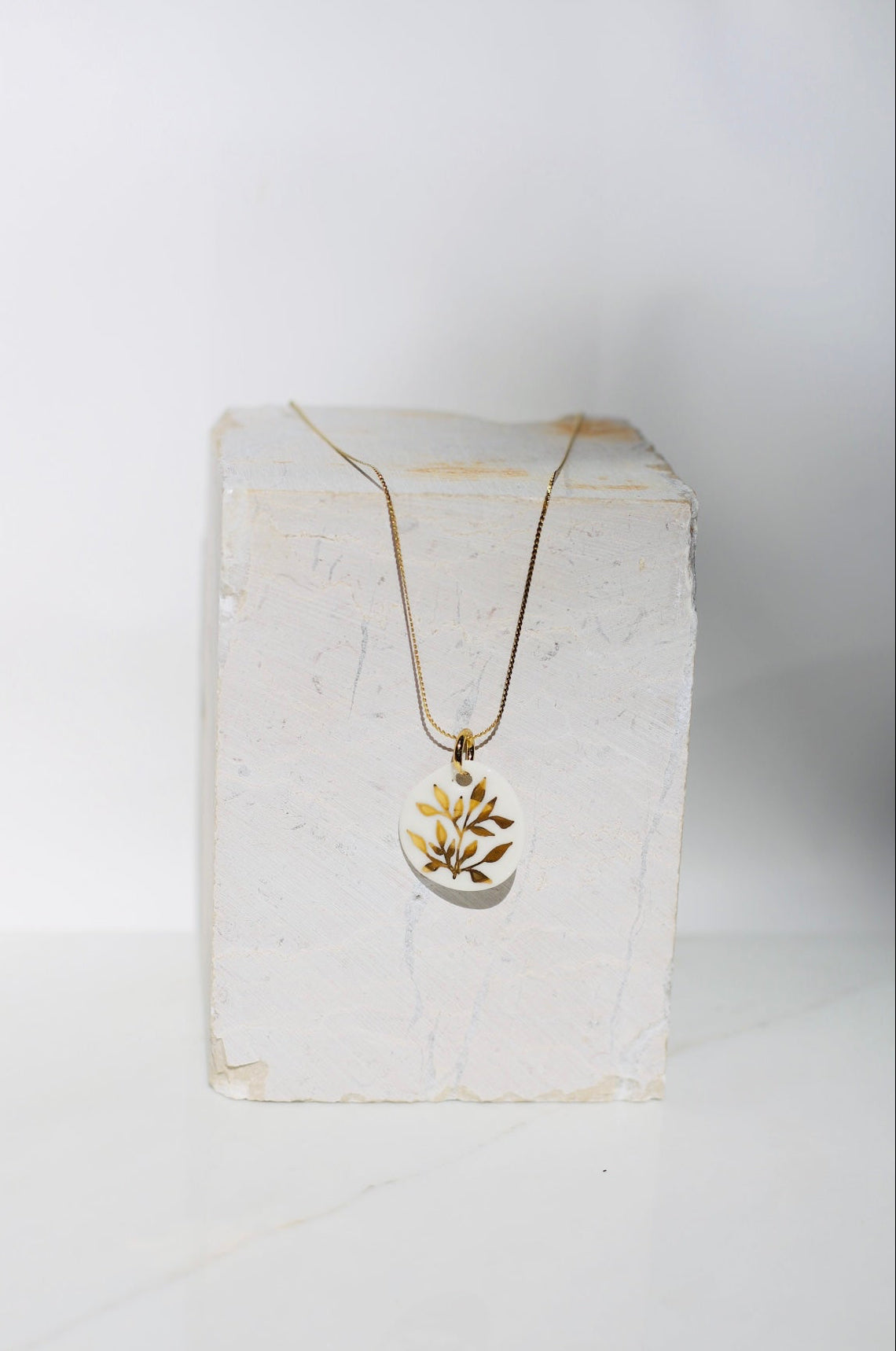 collier avec un pendentif en porcelaine fait main avec des détails floraux peint à l'or liquide 