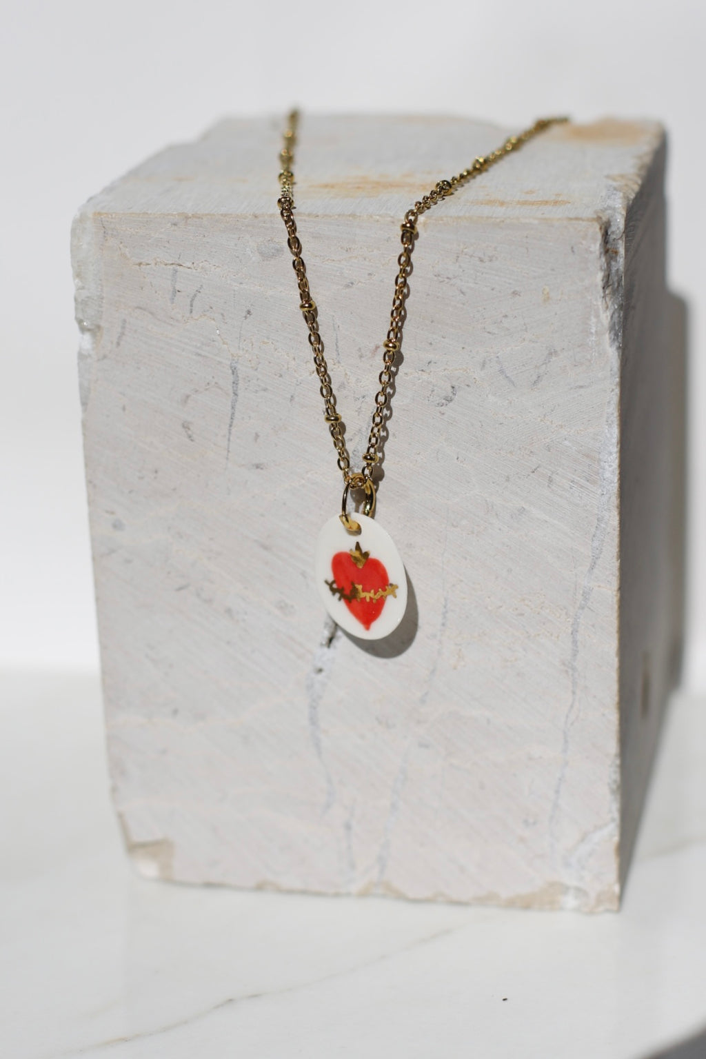 pendentif en porcelaine fait à la main avec un motif coeur enflammée avec des détails à l'or peint à la main à Lyon 