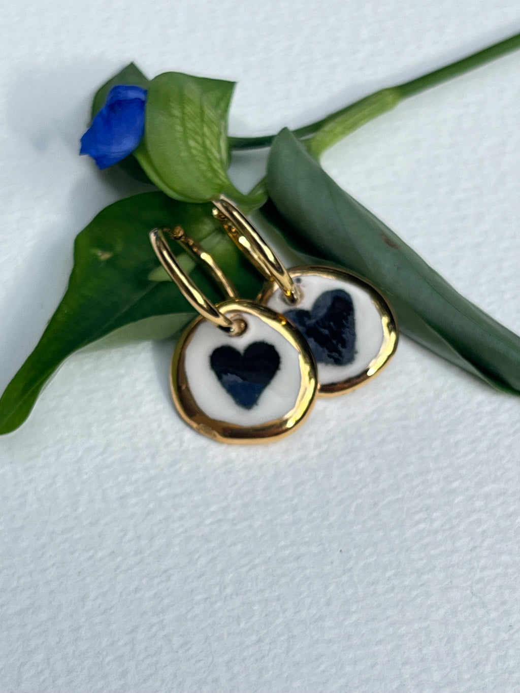 boucles d'oreilles  pendante en porcelaine blanche, avec motif en cœur noir central et l'éclat de la bordure dorée à l'or liquide.