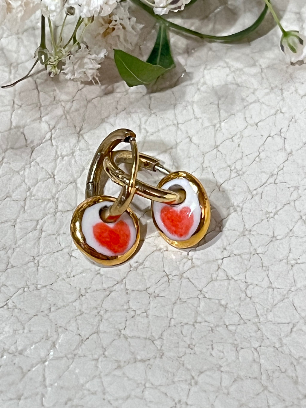 boucles d'oreilles dorés en porcelaine blanche affichant un cœur rouge 
entouré d'or fait à Lyon artisanalement 