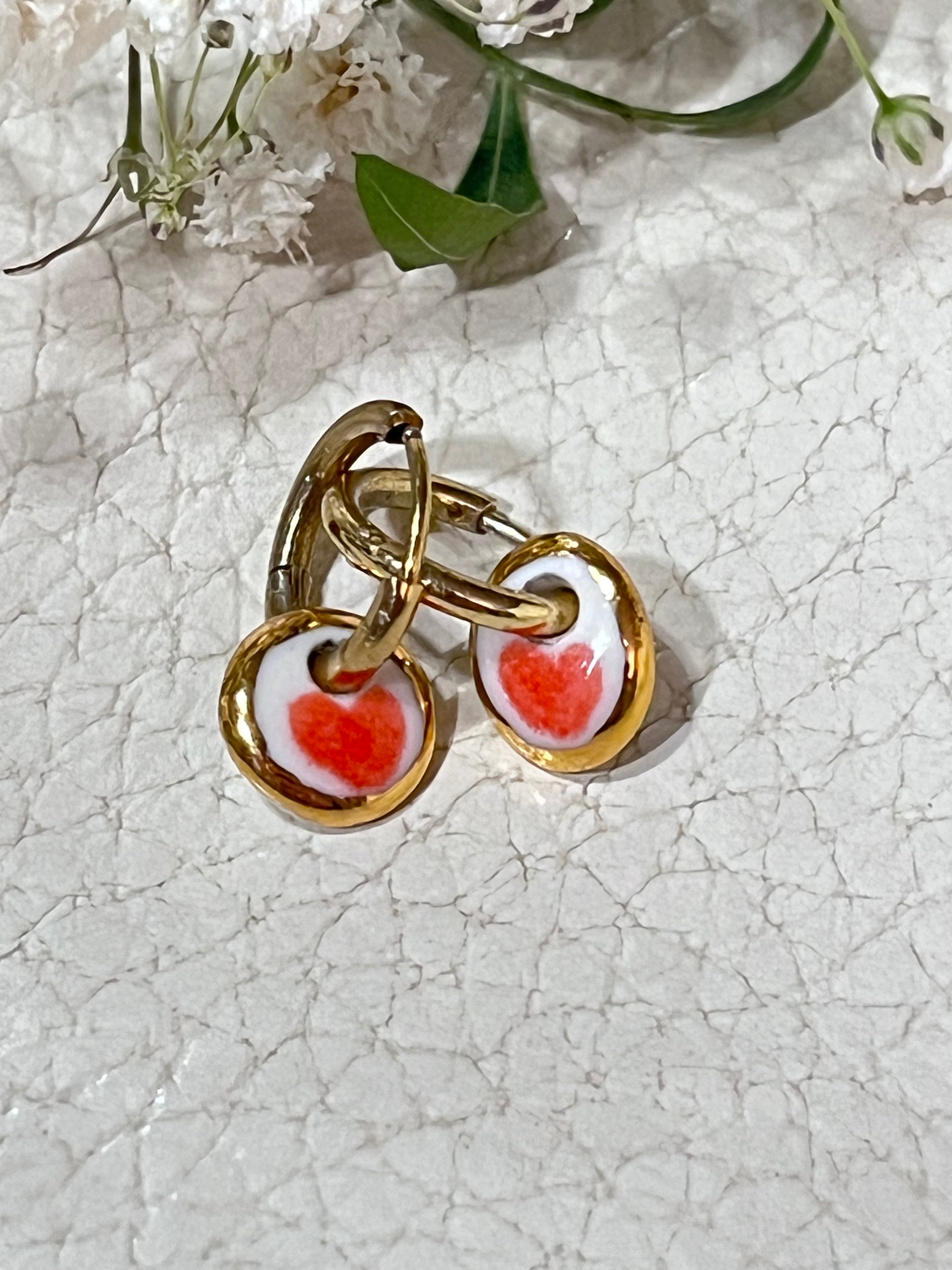 boucles d'oreilles dorés en porcelaine blanche affichant un cœur rouge 
entouré d'or fait à Lyon artisanalement 