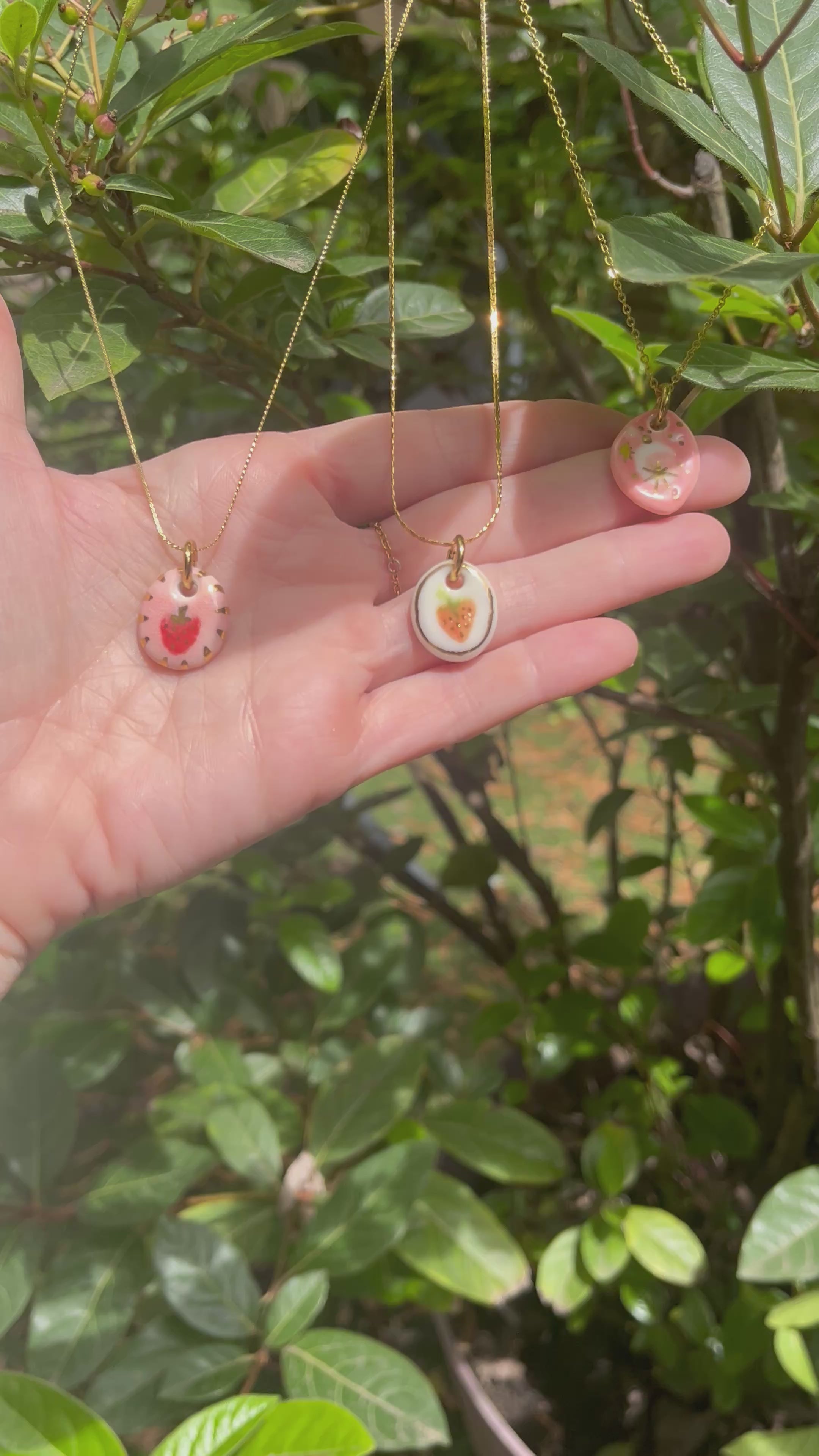 collier en porcelaine avec un pendentif rom avec une fraise peinte à la main avec des touches d'or liquide