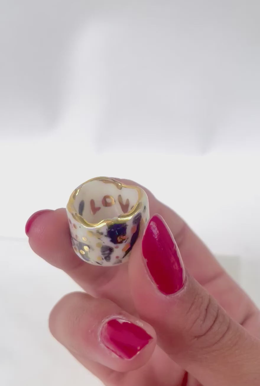 bague auriculaire en porcelaine émaillée blanche en taille 47 FR, avec un motif  abstrait de taches d'encre noires intenses et des touches d'or brillant.