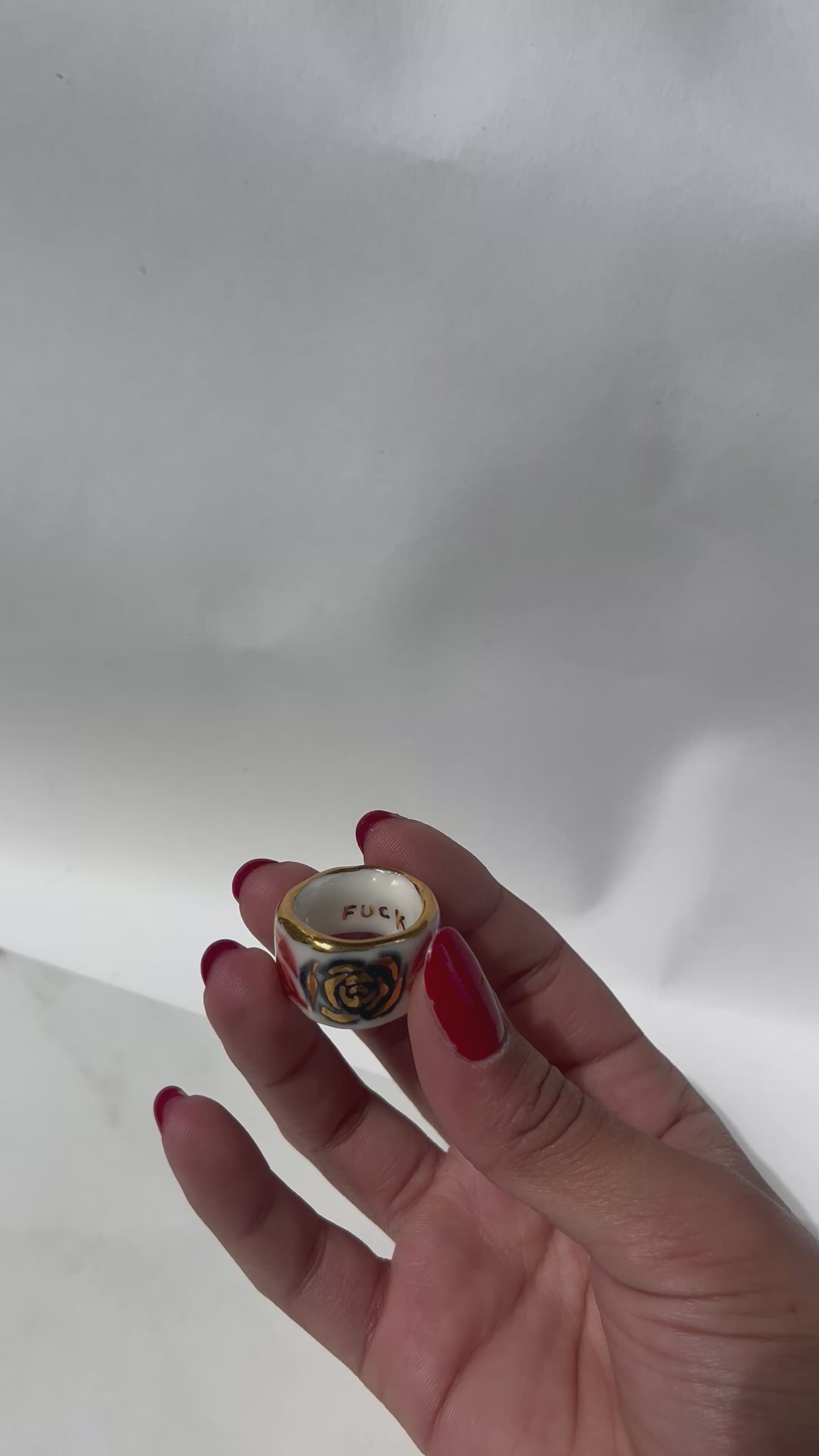 Une bague en porcelaine blanche émaillée en taille 51. Avec un motif rose noire stylisée peinte à l'or liquide avec des feuilles colorées. Avec une inscription  cachée "LOVE" en lettres dorées. Réalisée à la main à Lyon. 
