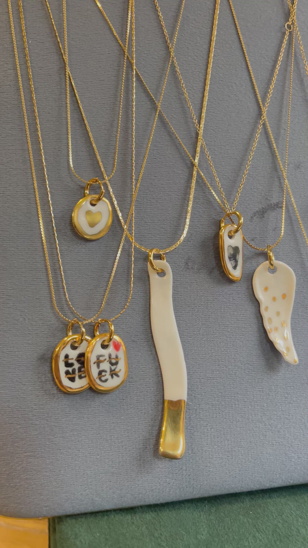 collier avec un pendentif en céramique où le mot love y est peint à l'or liquide