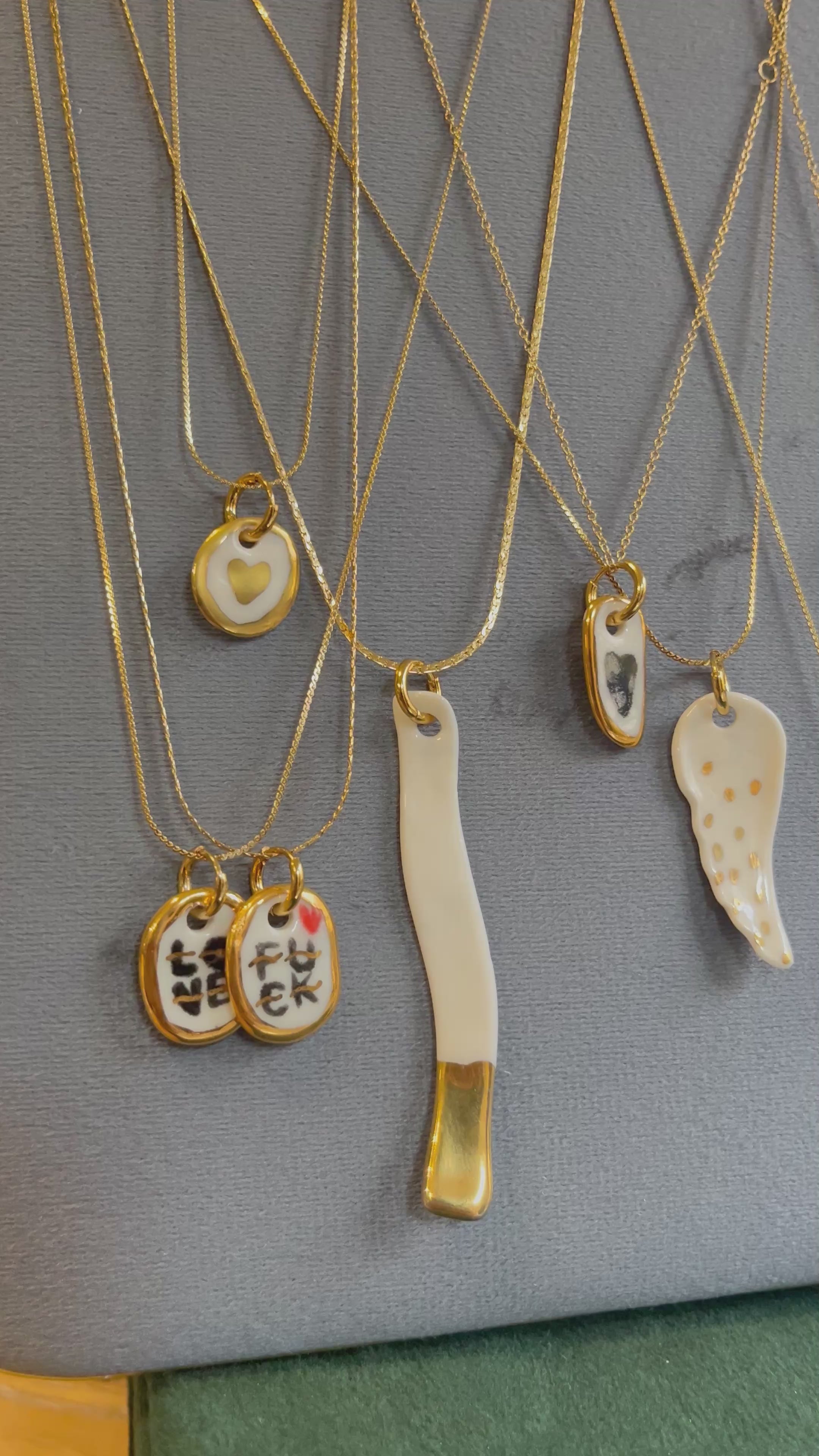 collier avec un pendentif en céramique où le mot love y est peint à l'or liquide
