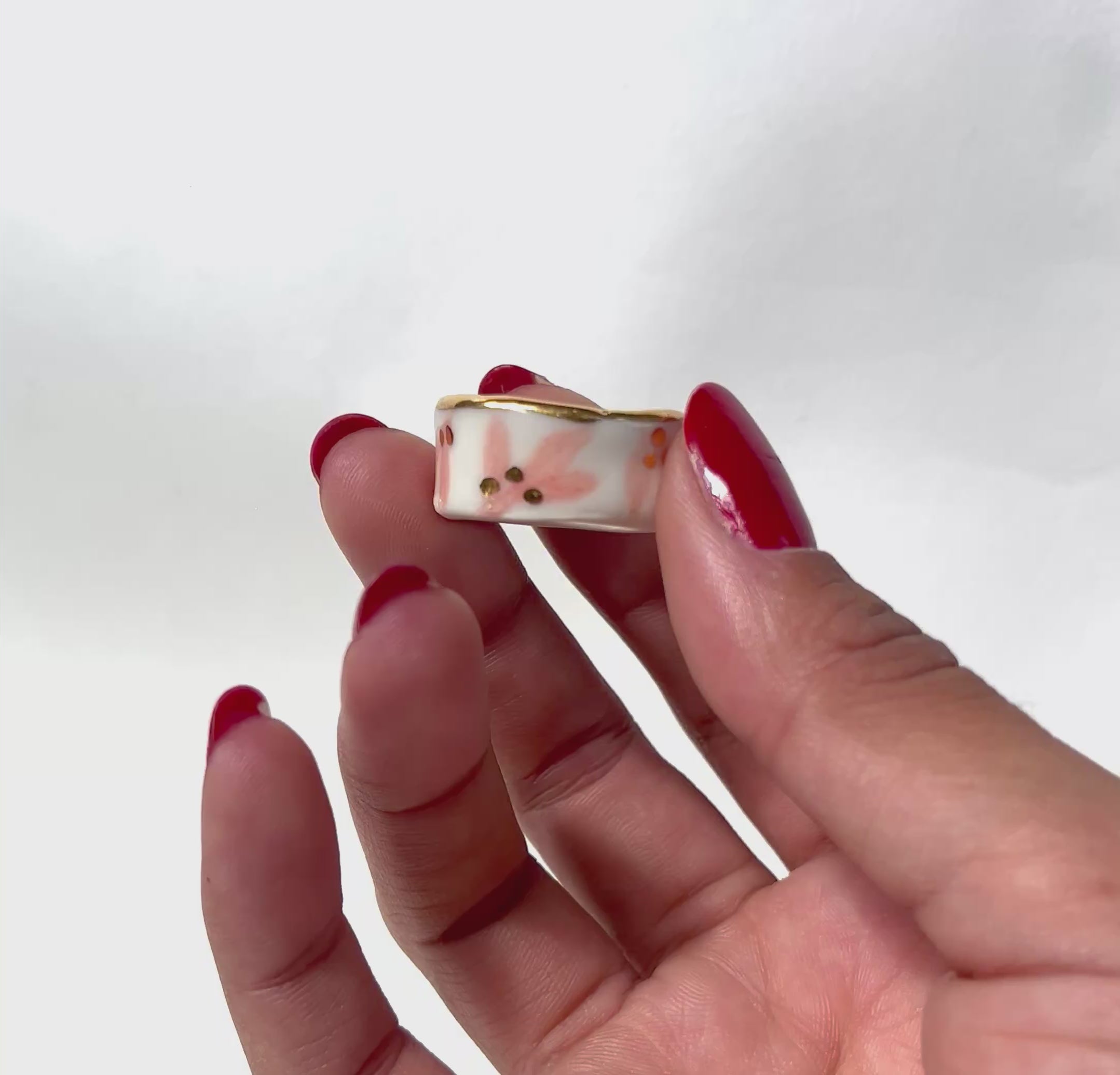 bague en porcelaine blanche émaillée en taille 53 Fr, à motif fleurs rose et de points à l'or liquide fait à la main avec un liseré doré sur sa tranche.